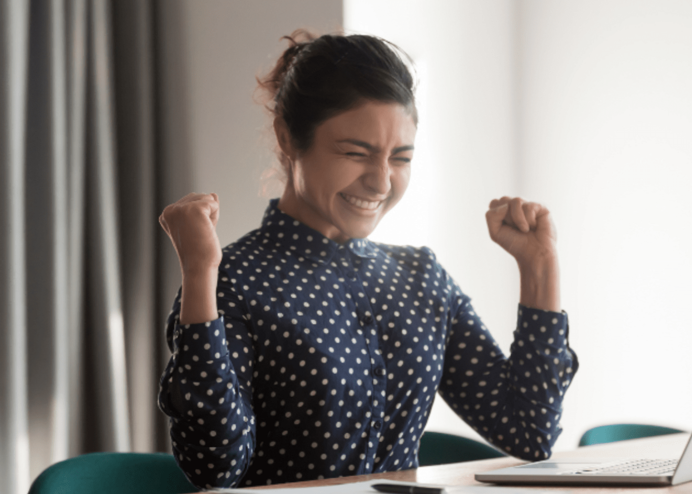 Women in business wear looking excited at her laptop