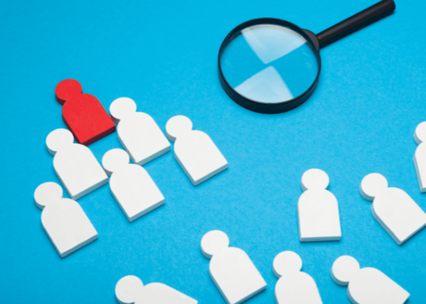 A magnifying glass hovering over blocks shaped like people searching for the red block