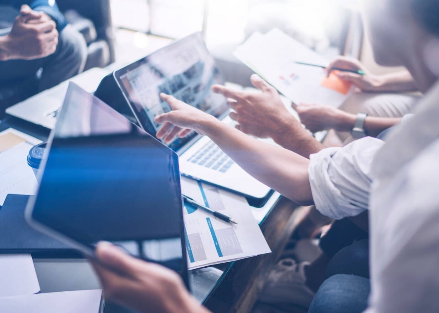 Business people sitting around a computer, an IT professional is pointing at the computer screen