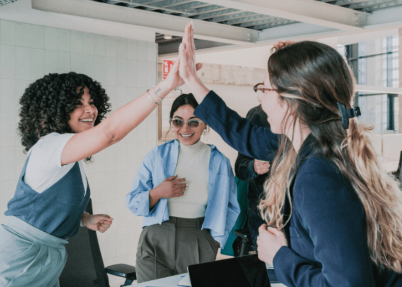 A group of female professionals excited and high-fiving in a circle