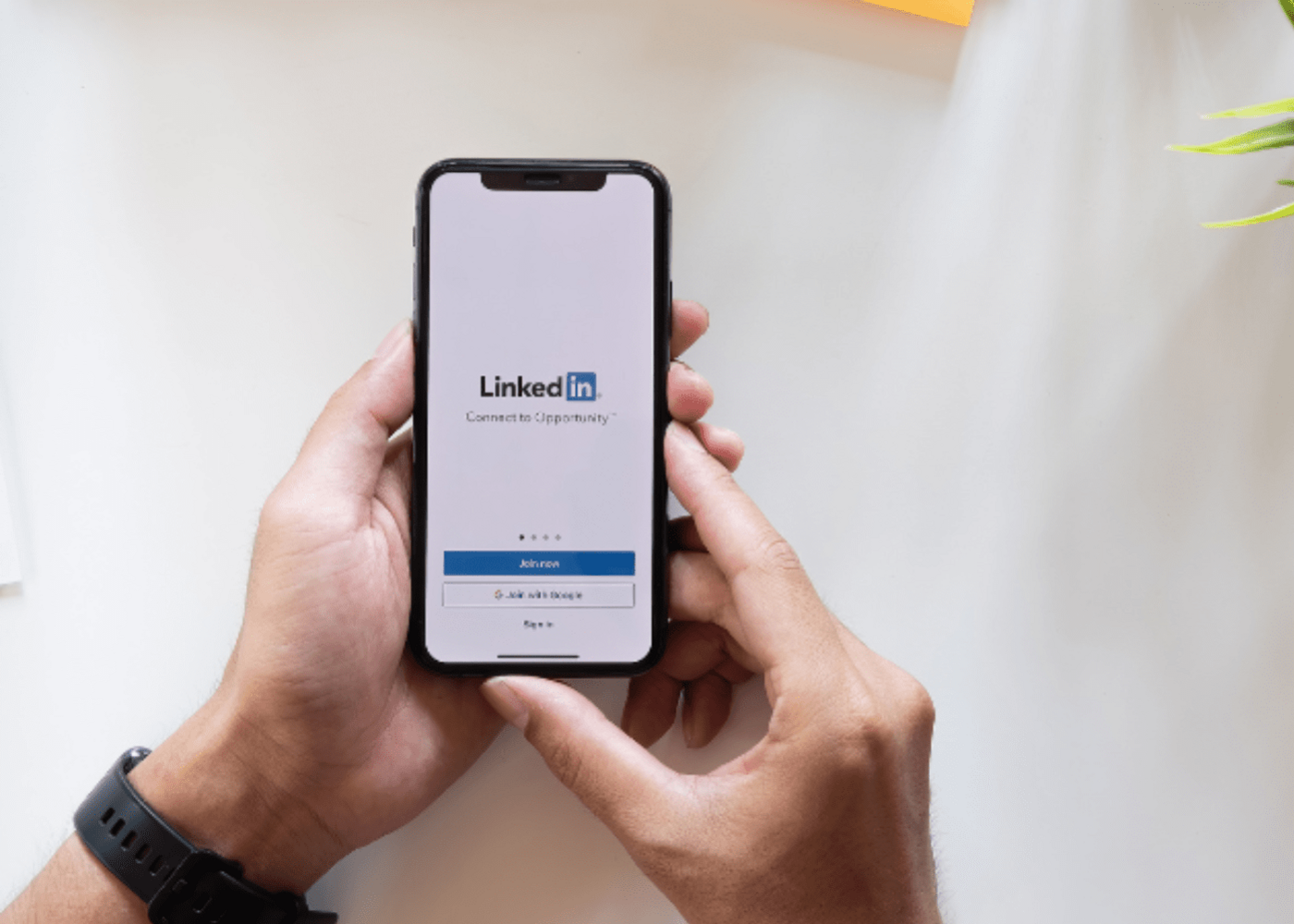 Hands holding a phone with the screen loading the social media app, LinkedIn