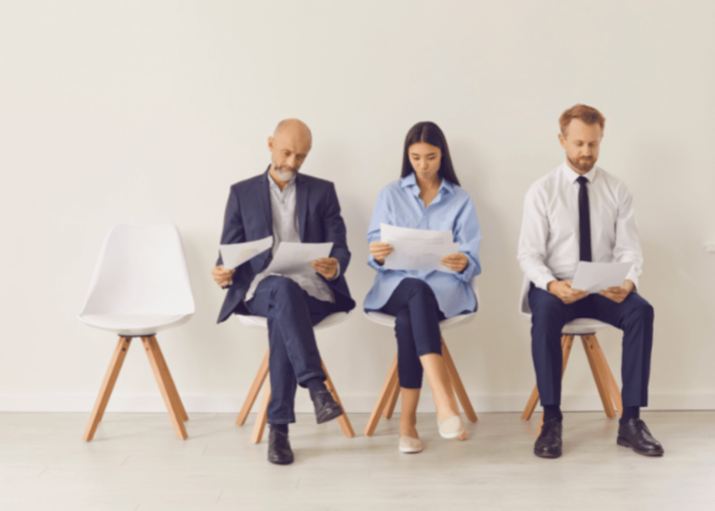 Three business people sitting in chairs waiting with one person missing