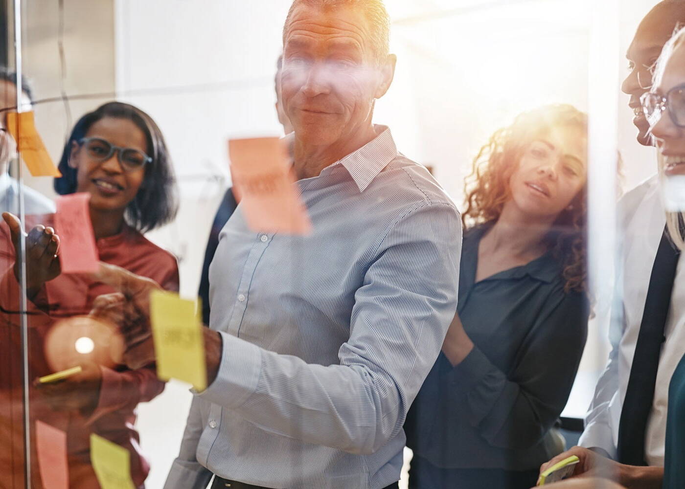 Business people brainstorming around a board with sticky notes