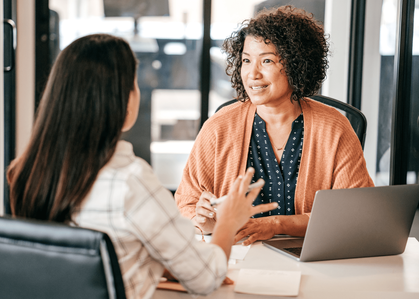 Two women sitting across from each other during a job interview, engaged in a professional conversation.