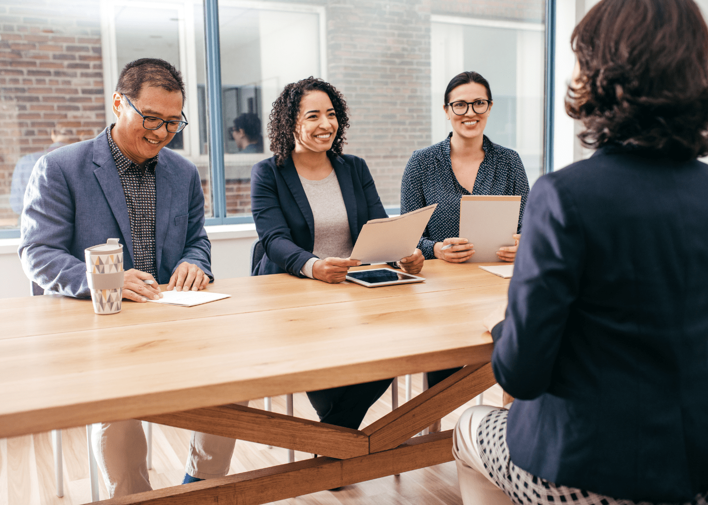 A female job candidate interviewing for a position in front of 3 other business professionals